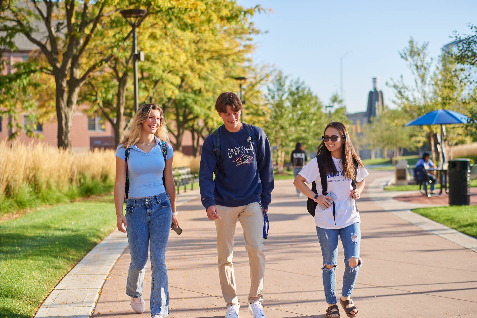 Three students walking downtown with backpacks, outside of Seidman College of Business